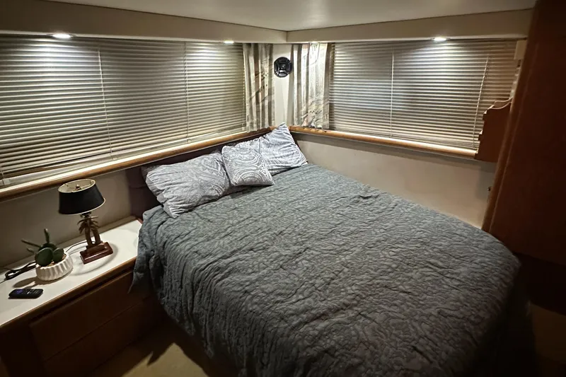 Slide: The Image of 1991 Carver 33 Aft Cabin bedroom with cozy bed, soft lighting, and window blinds. - 36