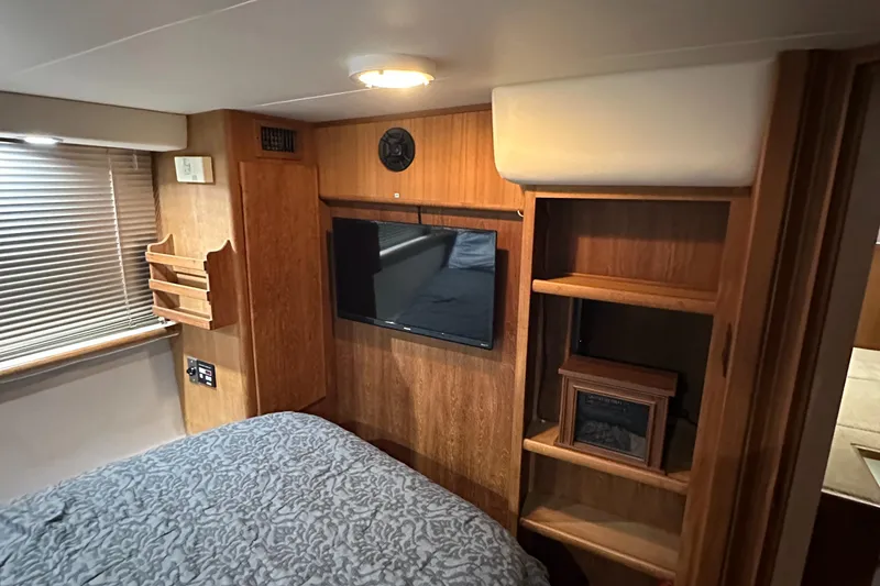 Slide: The Image of 1991 Carver 33 Aft Cabin interior with bed, TV, and wooden shelves. - 37