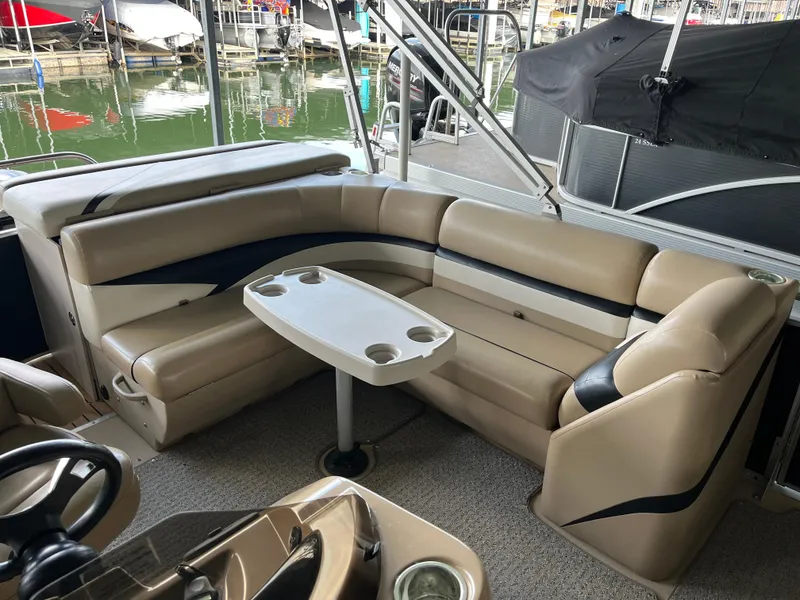 Slide: The Image of 2014 Harris Cruiser 240 interior with beige seating and table, docked at marina. - 13