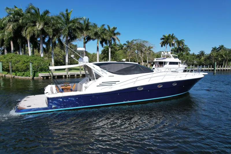 Slide: The Image of 1999 Uniesse 57 Open yacht cruising on a sunny day near palm trees. - 11