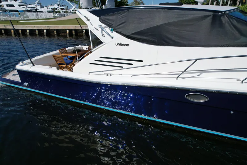 Slide: The Image of 1999 Uniesse 57 Open yacht docked, featuring sleek design and spacious deck area. - 18