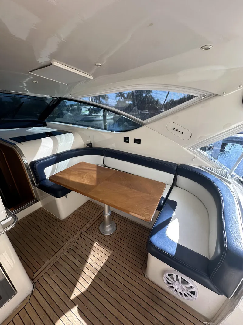 Slide: The Image of 1999 Uniesse 57 Open yacht interior with wood table and blue cushioned seating. - 22