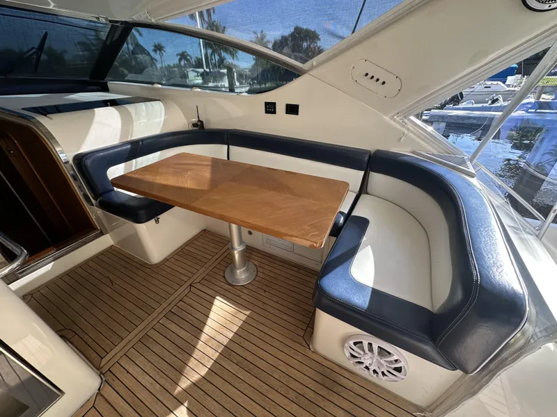 Slide: The Image of Interior of 1999 Uniesse 57 Open yacht with wooden table and cushioned seating. - 24