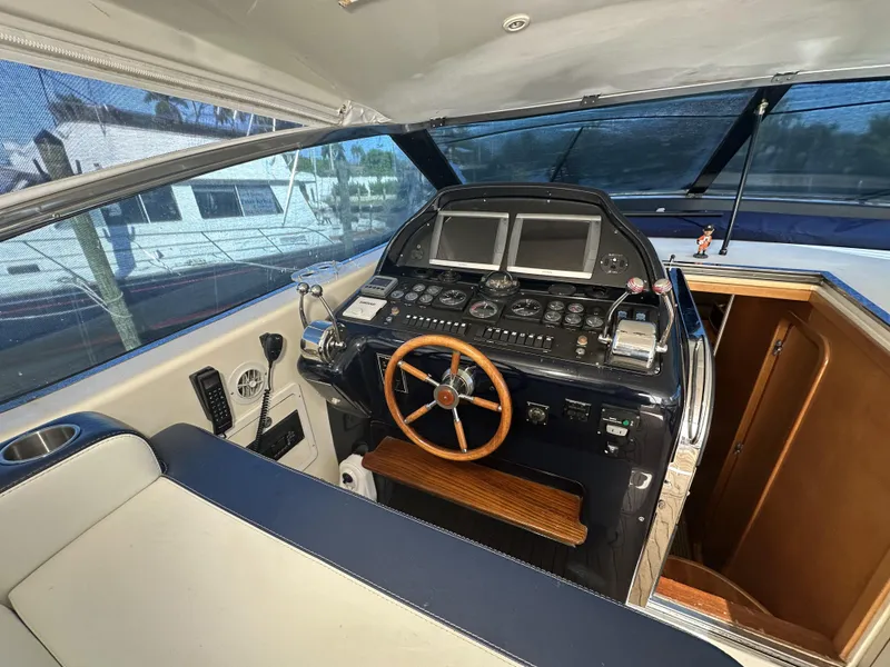 Slide: The Image of 1999 Uniesse 57 Open yacht helm with wooden steering wheel and dual displays. - 29