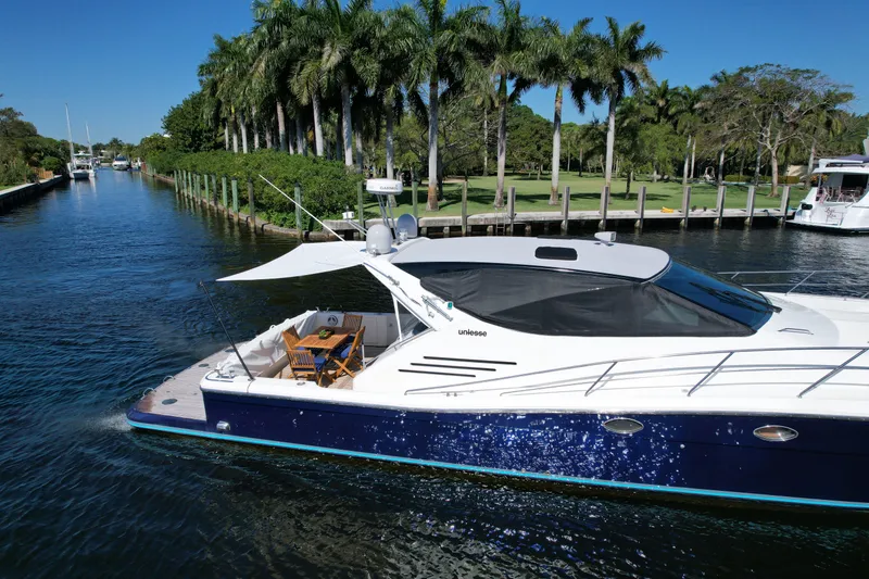 Slide: The Image of 1999 Uniesse 57 Open yacht cruising on a scenic waterway with palm trees. - 6