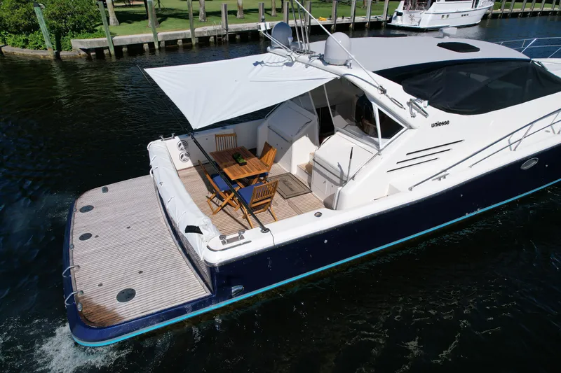 Slide: The Image of 1999 Uniesse 57 Open yacht with outdoor seating, cruising on a calm waterway. - 9