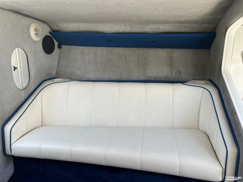 Slide: The Image of Interior of a 2002 Nordic 28 Heat MCOB boat with white seating and blue accents. - 13