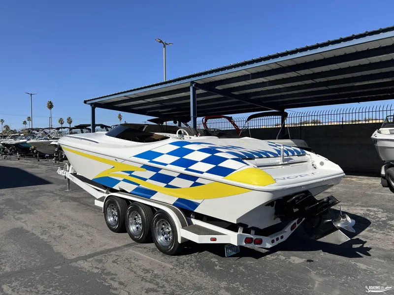 Slide: The Image of 2002 Nordic 28 Heat MCOB boat with vibrant blue and yellow graphics on a trailer. - 2
