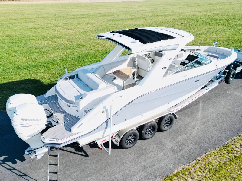 Slide: The Image of 2023 Sea Ray SLX 310 OB boat on trailer, parked on grass. - 2