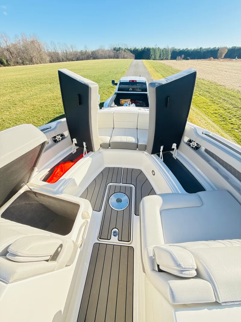 Slide: The Image of 2023 Sea Ray SLX 310 OB boat interior with open storage compartments, parked on grass. - 36
