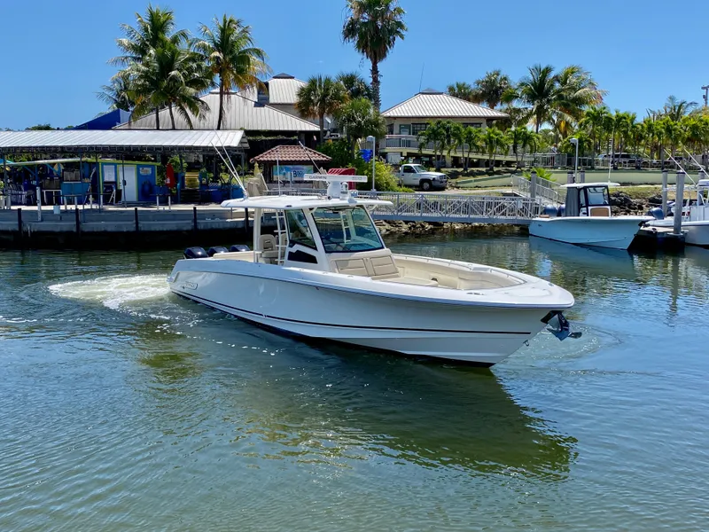 Slide: The Image of 2019 Boston Whaler 380 Outrage boat cruising near a marina with palm trees. - 3