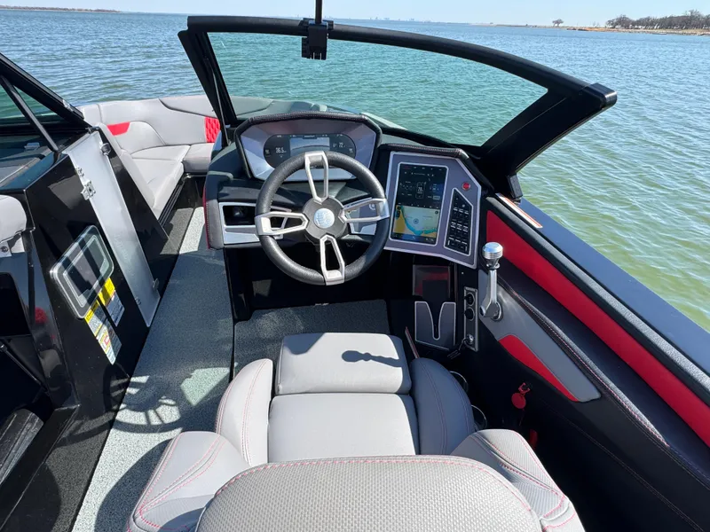 Slide: The Image of 2022 MasterCraft XT24 boat interior with modern dashboard and steering wheel on a lake. - 11