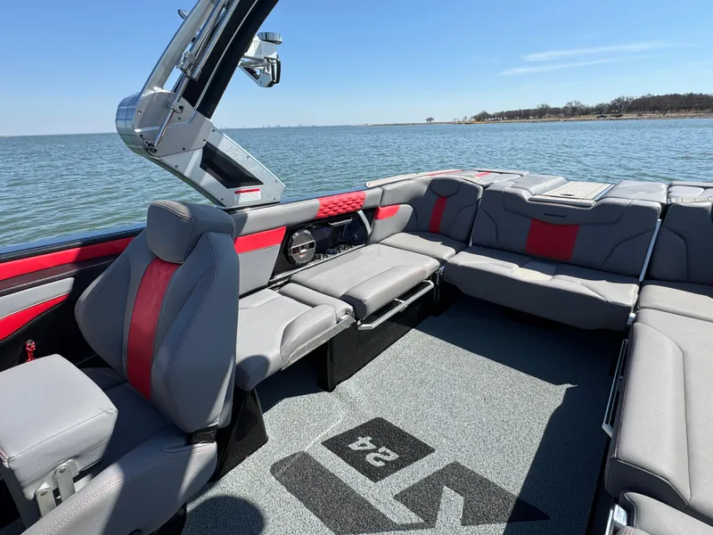 Slide: The Image of 2022 MasterCraft XT24 boat interior with gray and red seating on a sunny day. - 16
