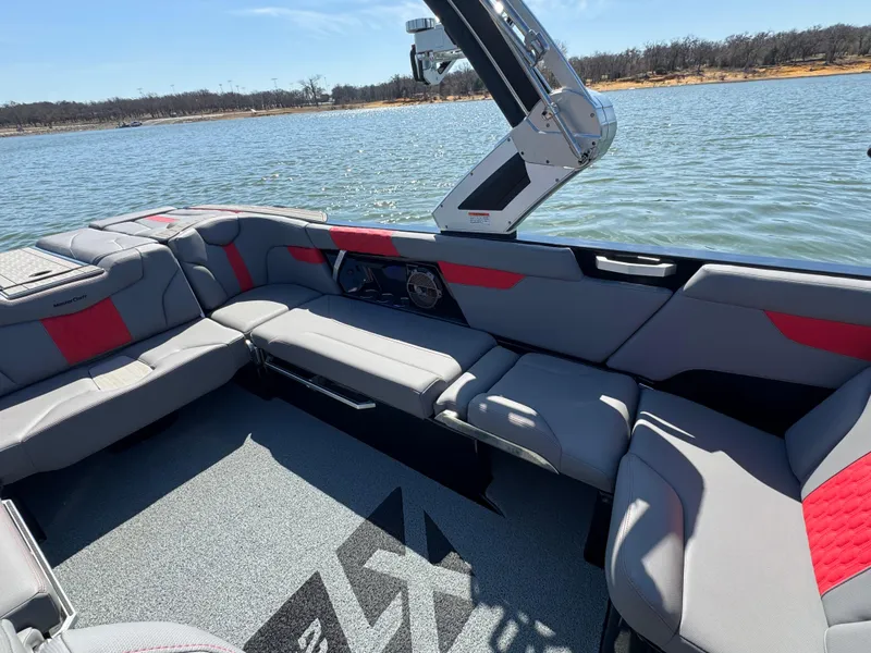 Slide: The Image of 2022 MasterCraft XT24 boat interior with gray and red seating on a lake. - 17
