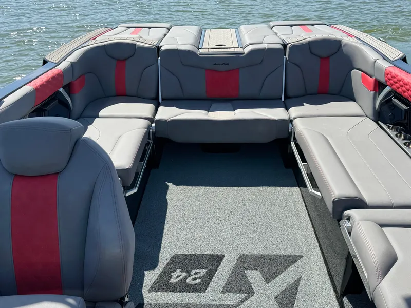 Slide: The Image of 2022 MasterCraft XT24 boat interior with gray and red seating on the water. - 19