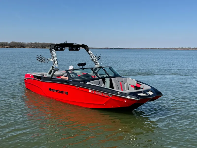 Slide: The Image of 2022 MasterCraft XT24 boat in red on a calm lake. - 2