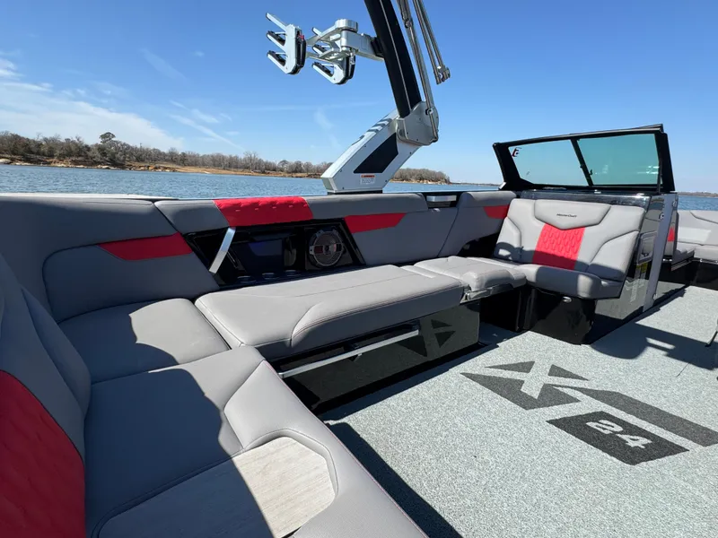 Slide: The Image of 2022 MasterCraft XT24 boat interior with gray and red seating, on a sunny day. - 20