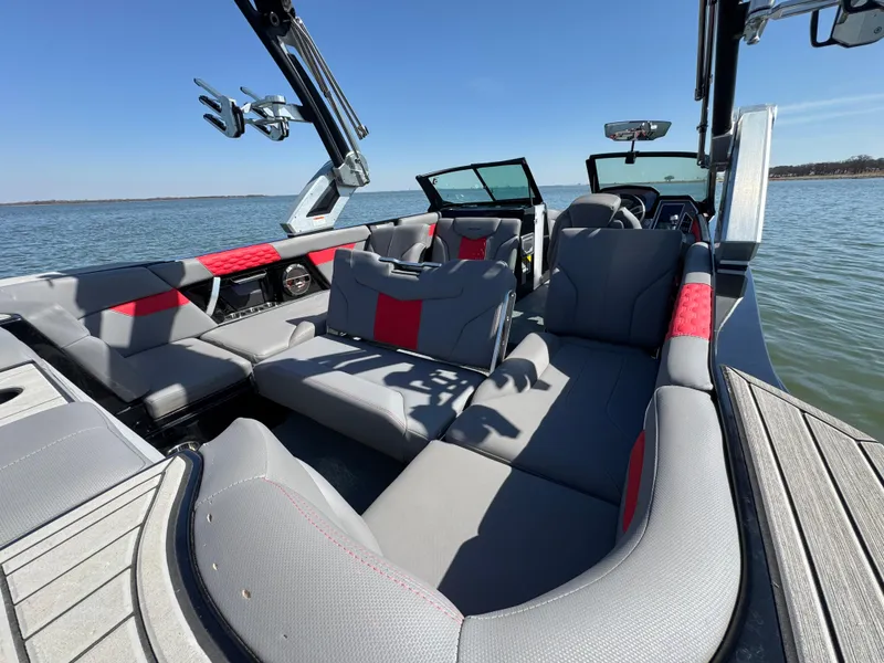 Slide: The Image of 2022 MasterCraft XT24 boat interior with gray and red seating on a sunny day. - 25