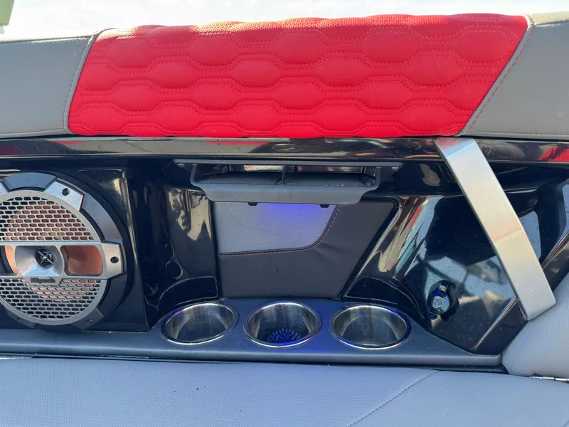 Slide: The Image of 2022 MasterCraft XT24 interior with speaker, cup holders, and red upholstery detail. - 27