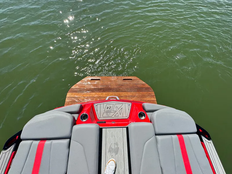 Slide: The Image of 2022 MasterCraft XT24 boat with red and gray seating, overlooking sparkling water. - 32