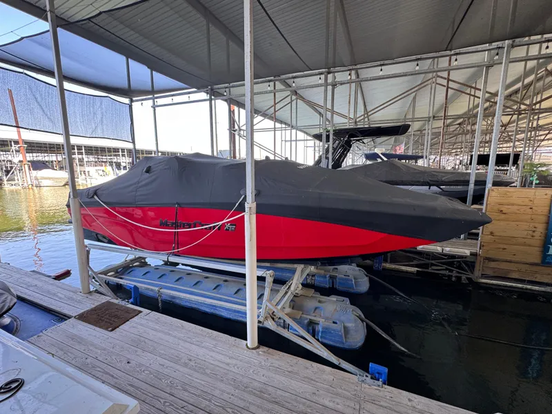 Slide: The Image of 2022 MasterCraft XT24 boat, red with cover, docked in a marina. - 36