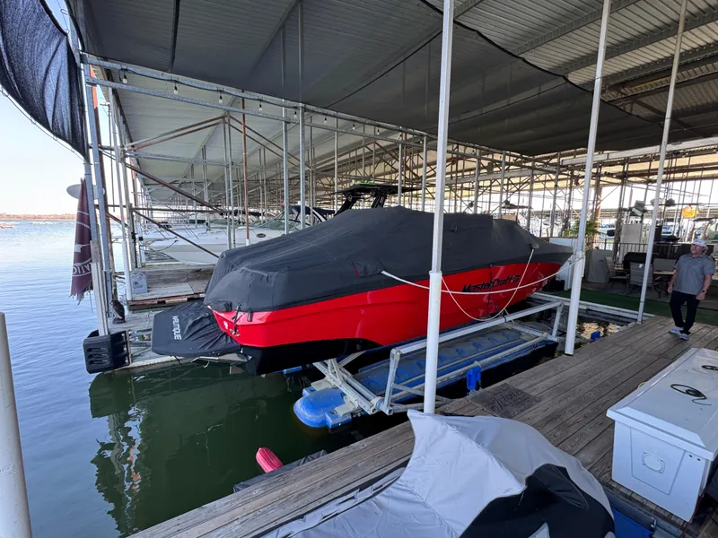 Slide: The Image of 2022 MasterCraft XT24 boat covered and docked in a marina. - 37