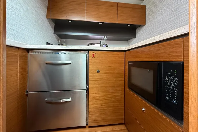 Slide: The Image of Modern galley kitchen in 2020 Tiara Yachts 39 Coronet, featuring wood cabinetry and stainless appliances. - 31