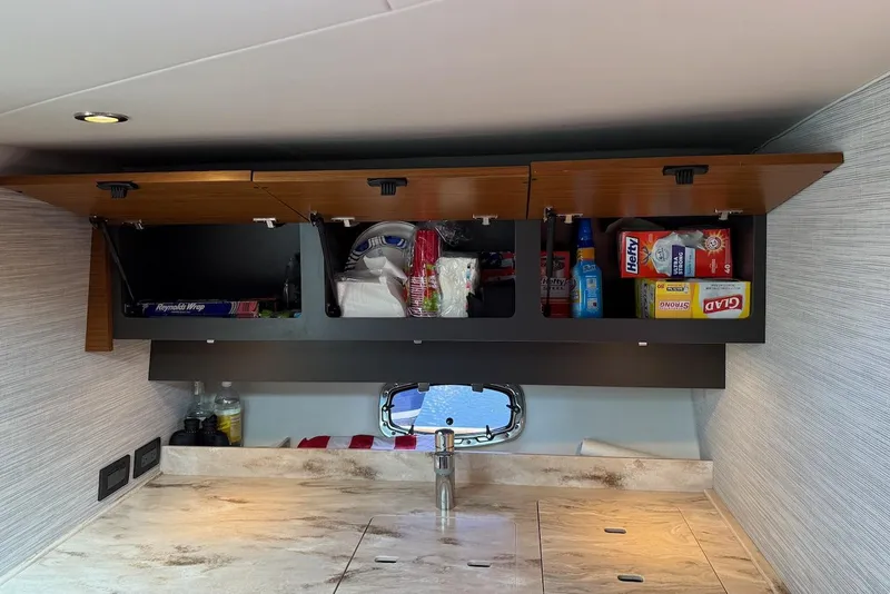 Slide: The Image of Interior of 2020 Tiara Yachts 39 Coronet with open cabinets and kitchen supplies. - 34