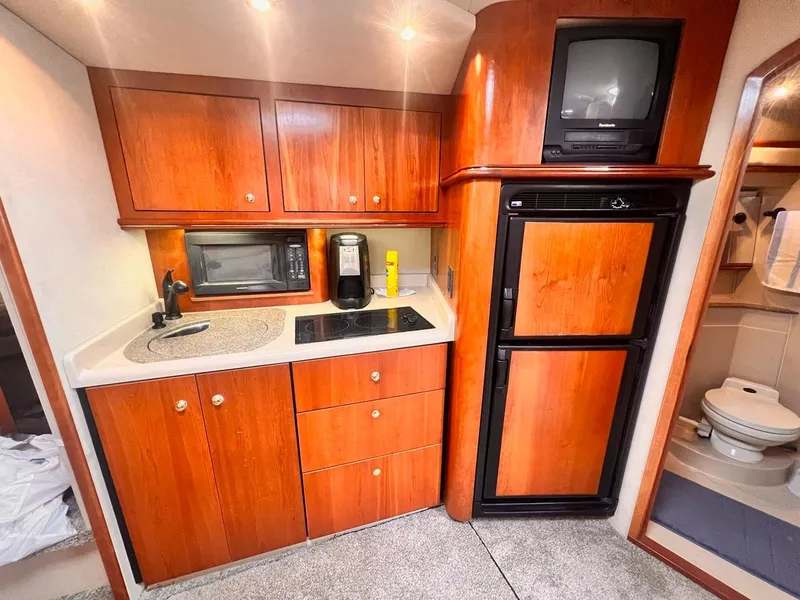 Slide: The Image of 2001 Cruisers Yachts 3870 Express interior kitchen with wood cabinets, sink, and appliances. - 16