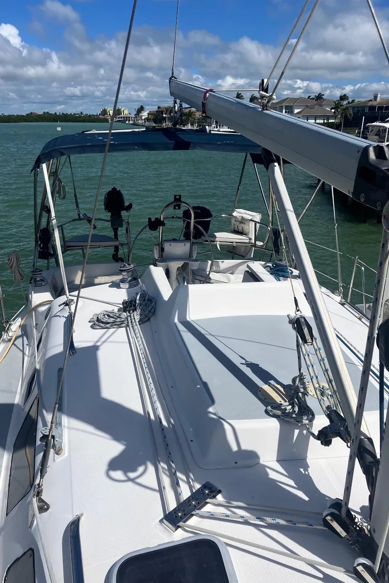 Slide: The Image of 2003 Hunter 326 sailboat on water, clear sky, marina in background. - 10