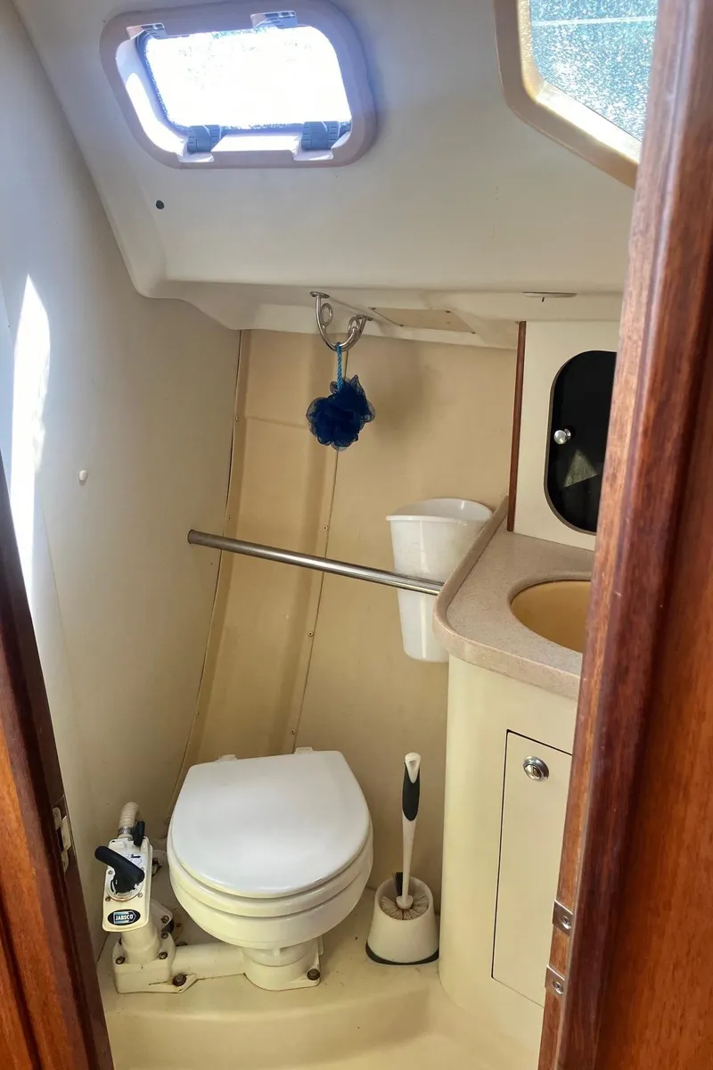 Slide: The Image of 2003 Hunter 326 sailboat bathroom with toilet, sink, and window. - 11
