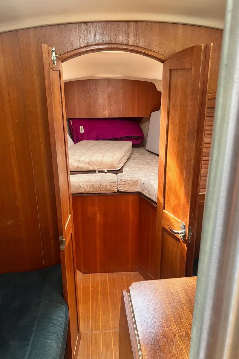 Slide: The Image of 2003 Hunter 326 sailboat interior cabin with wooden finish and cozy bedding. - 16