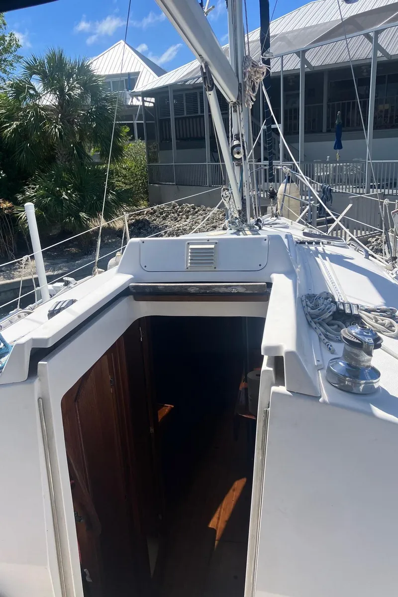 Slide: The Image of 2003 Hunter 326 sailboat deck with open cabin entrance, docked near buildings. - 9