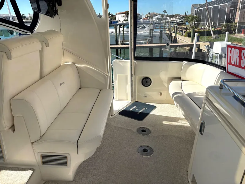 Slide: The Image of 2006 Cruisers Yachts 415 Express Motoryacht interior with white seating, dock view, and "For Sale" sign. - 14