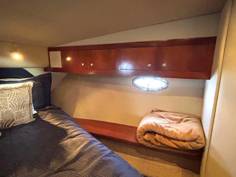 Slide: The Image of 2006 Cruisers Yachts 415 Express Motoryacht cabin with bed, wooden cabinets, and porthole window. - 45