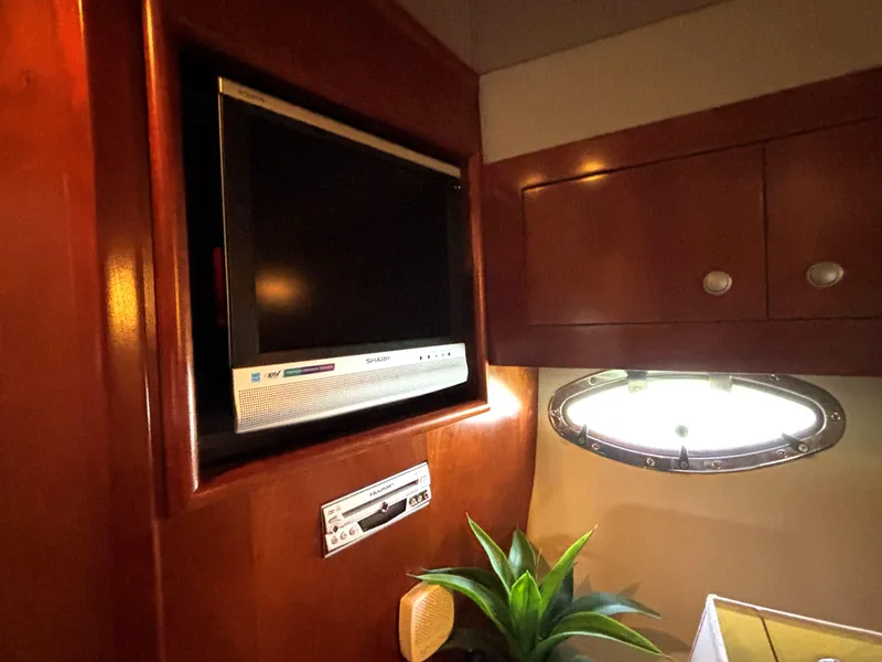 Slide: The Image of 2006 Cruisers Yachts 415 Express Motoryacht interior with TV, porthole, and wooden cabinetry. - 47