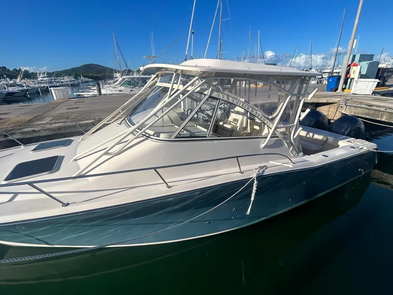Slide: The Image of 2021 Grady-White Express 330 boat docked in a marina under clear blue skies. - 3