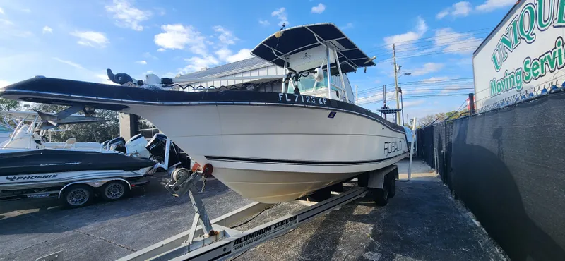 Slide: The Image of 1999 Robalo 2420 Center Console boat on trailer, parked outdoors under blue sky. - 6