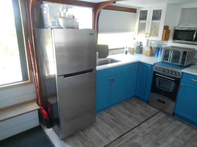 Slide: The Image of 1975 Marine Trader 40 Double Cabin kitchen with blue cabinets and modern appliances. - 27