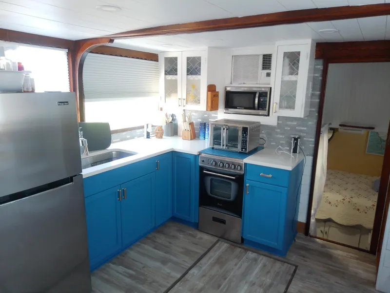 Slide: The Image of 1975 Marine Trader 40 Double Cabin kitchen with blue cabinets, stainless appliances, and modern decor. - 28