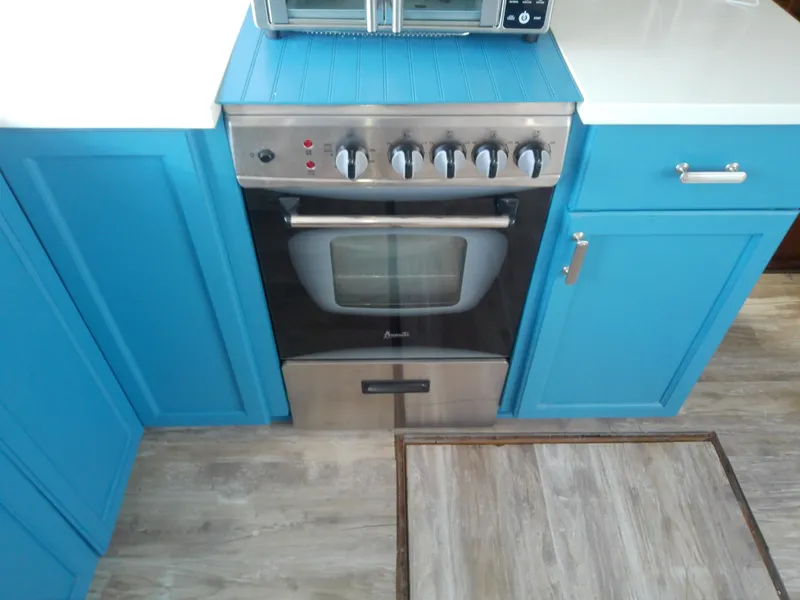 Slide: The Image of Stainless steel oven in a 1975 Marine Trader 40 Double Cabin kitchen with blue cabinets. - 31
