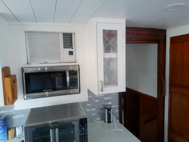 Slide: The Image of 1975 Marine Trader 40 Double Cabin kitchen with microwave, air conditioner, and wooden cabinetry. - 34