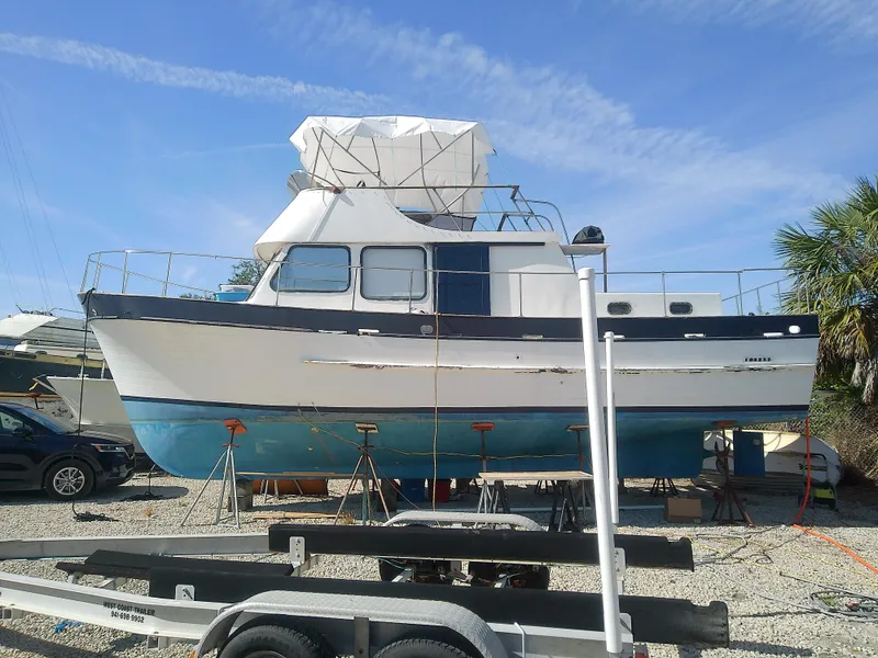 Slide: The Image of 1975 Marine Trader 40 Double Cabin boat on stands, blue and white hull, sunny day. - 7