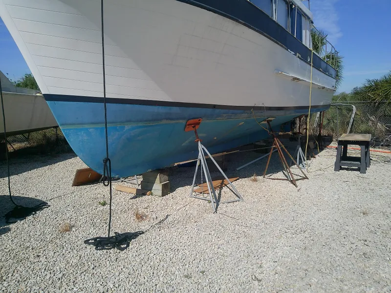 Slide: The Image of 1975 Marine Trader 40 Double Cabin on dry dock, supported by stands, gravel ground. - 8