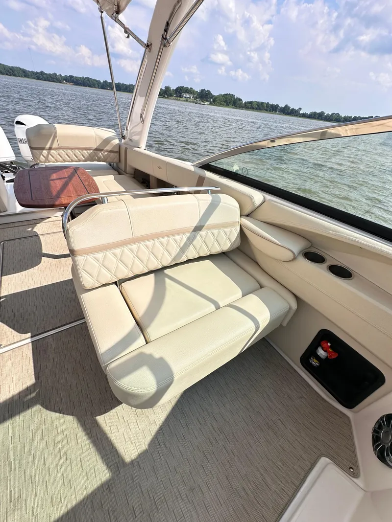 Slide: The Image of 2019 Regal 29 OBX boat interior with beige seating, on a sunny day by the water. - 13