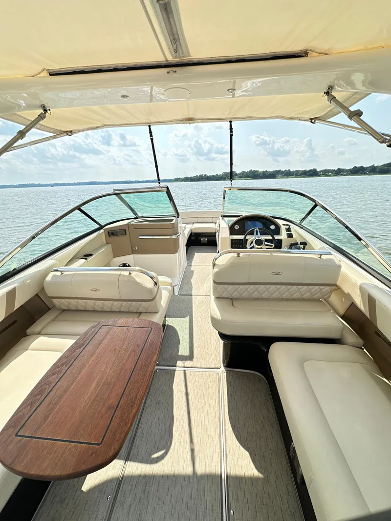 Slide: The Image of 2019 Regal 29 OBX boat interior with luxurious seating and wooden table on a sunny day. - 15