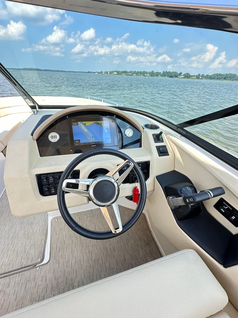 Slide: The Image of 2019 Regal 29 OBX boat cockpit with steering wheel and navigation system on a sunny day. - 16