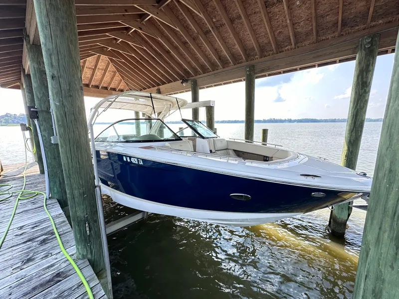 Slide: The Image of 2019 Regal 29 OBX boat docked under a wooden shelter on a lake. - 2