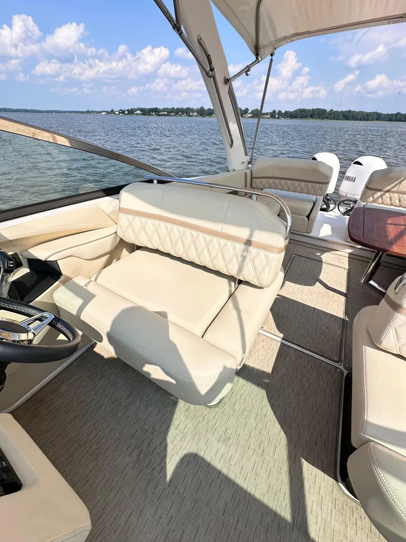Slide: The Image of 2019 Regal 29 OBX boat interior with beige seating, steering wheel, and lake view. - 32
