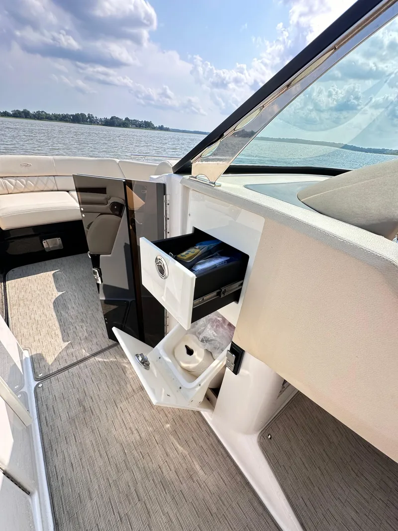 Slide: The Image of 2019 Regal 29 OBX boat interior with open storage compartments, on a sunny day by the water. - 35
